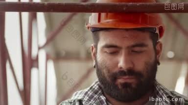 年轻的西班牙人在建筑工地工作的肖像，严肃的手工工人戴着头盔看着相机